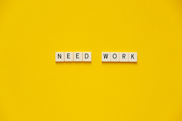 Phrase Need work. Blocks with letters on a yellow background. The concept of job search during the crisis