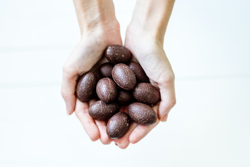 The girl generously treats friends with chocolates. Chocolate in the hand.