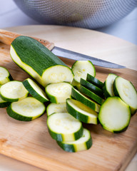 Chopping zucchini with a knife on a wooden board. 