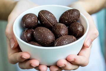 The girl generously treats friends with chocolates. Chocolate in the hand.
