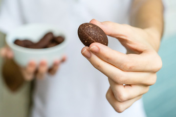 The girl generously treats friends with chocolates. Chocolate in the hand.