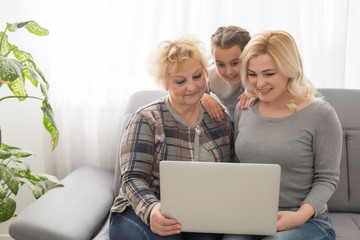 Grandmother and daughter teaching child use laptop application, playing game