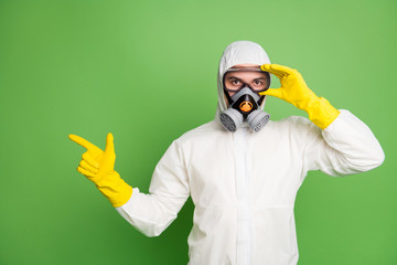 Portrait of his he nice confident professional disinfectant wearing touching fixing gas mask showing copy space quarantine restrictions news isolated over green pastel color background