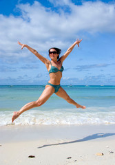 Frau im Bikini springt am Strand
