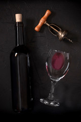 Wine tasting, overhead shot on a black background, with a cork, corkscrew, and a bottle