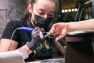 Close-up of hardware milling cutter for removing gel polish. Apparatus manicure in beauty salon. Manicurist with electric nail drill remove old gel from client nails. Process of replacing old shellac.