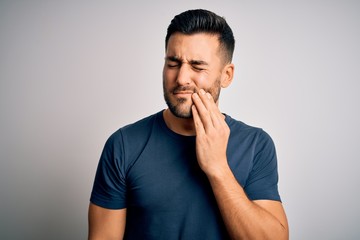 Young handsome man wearing casual t-shirt standing over isolated white background touching mouth...