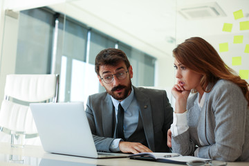 Obraz premium Businessman and businesswoman looking into the laptop screen in shock