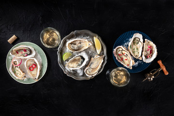 Oysters with various toppings, shot from the top, with lemon and lime, pepper, onion, on a black background with a place for text