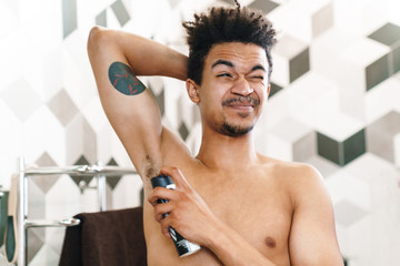 Photo of african american man using deodorant for his armpits