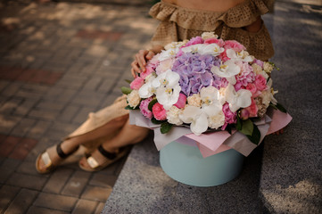 large bright flower arrangement in round box stands on the steps.