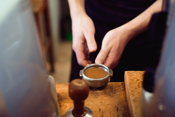 Fototapeta na wymiar Barista presses ground coffee using tamper in a coffe shop