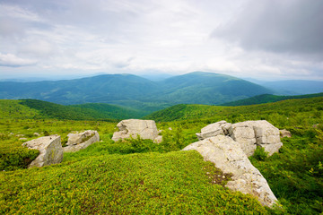 huge stones in valley on top of mountain ridge. mountain summer landscape. meadow with huge stones among the grass on top of the hillside near the peak of mountain range