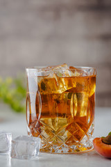 Glass of peach or apricot iced tea with fruit slices against white background