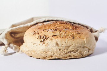 small loaf of homemade bread in a cloth bag on a white background