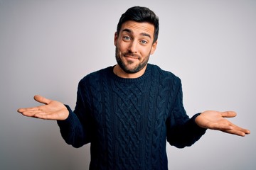 Young handsome man with beard wearing casual sweater standing over white background clueless and...
