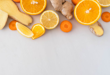 A flat lay style arrangement of citrus fruits and super food ingredients.  Food at top part of frame on white marble background with space for copy text