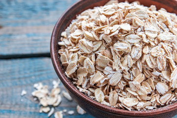 Bowl with raw oatmeal on a background of blue boards.
