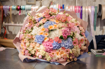 huge bouquet of various flowers lies on the table in floristic studio