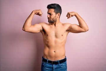 Fototapeta premium Young handsome strong man with beard shirtless standing over isolated pink background showing arms muscles smiling proud. Fitness concept.