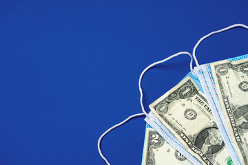 Close up of medical protective masks and american dollar banknotes on blue background