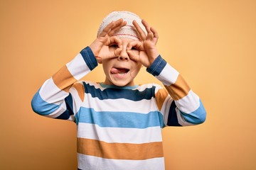 Young little caucasian kid injured wearing medical bandage on head over yellow background doing ok...