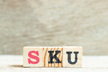 Alphabet letter in word SKU (abbreviation of stock keeping unit) on wood background