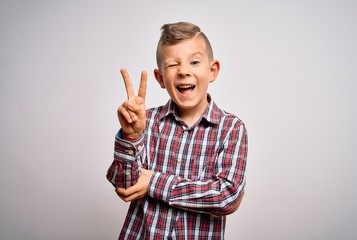Young little caucasian kid with blue eyes wearing elegant shirt standing over isolated background smiling with happy face winking at the camera doing victory sign with fingers. Number two.