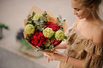 young woman holds stylish bouquet and looks at it
