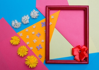 Frame and flowers lie on multi-colored paper.