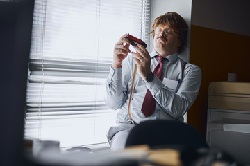 Funny accountant carefully studying the stapler in his hands
