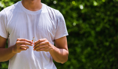 May 31 of World No Tobacco Day, Asian smoker man use hands breaking down cigarettes on green leaves background, Stop or quit smoking concept