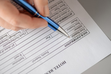 Woman filling hotel reservation form putting first name. Reception desk. Hotel service, registration. Close up. Selective focus.