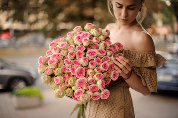 Fototapeta premium Young woman holds huge bright bouquet of ranunculus flowers