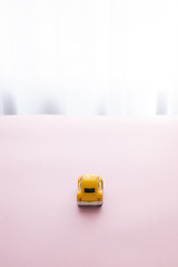 Minimal concept of small yellow toy car on a beautiful surface, rear view