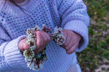 摘んだ花と花飾りを握る子供