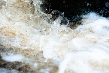 a small forest waterfall quickly runs over stones