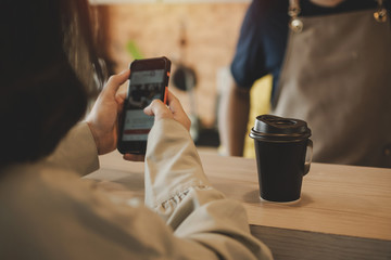 hot black coffee cup on top counter bar with woman customer using mobile phone and barista in modern cafe coffee shop, cafe restaurant, service mind, small business owner, food and drink concept