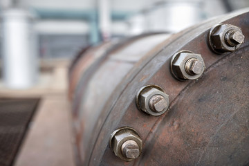 Bolted screw connection, sealing connection on manhole of industrial machine compressor or pump on chemical plant selective focus with out of focus abstract industrial background with copyspace.