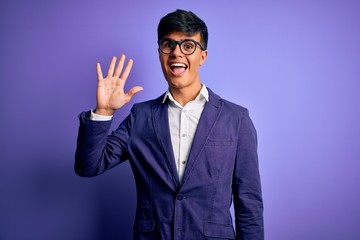 Young handsome business man wearing jacket and glasses over isolated purple background showing and pointing up with fingers number five while smiling confident and happy.