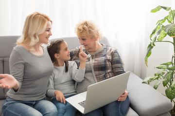 Grandmother and daughter teaching child use laptop application, playing game