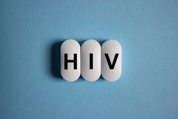 The inscription HIV on white tablets on a blue background. Human immunodeficiency virus concept.