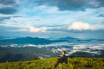 Fototapeta na wymiar man isolated watching the serene nature at hill top with amazing cloud layers in background