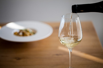 Glass of wine with wine ,gnocchi in a modern plate, day light