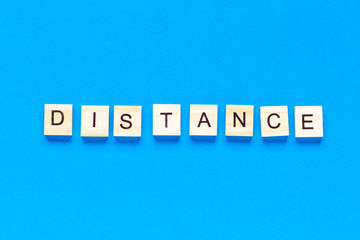 Words distance. Wooden inscription on a blue background. Information sign of distance from blocks on a blue background.
