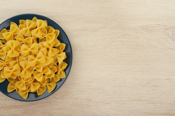 Raw pasta in the shape of a bow on a plate, top view, copy space