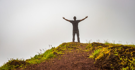 man isolated feeling the serene nature at hill top with amazing cloud layers in foreground
