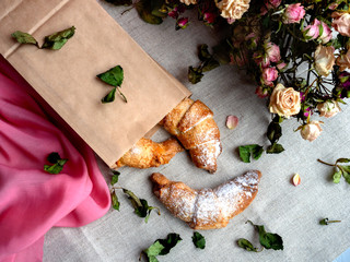 croissants in a paper bag on a linen background with flowers