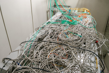 Many tangled wires are on top of the server racks of the data center. Internet communication cables...