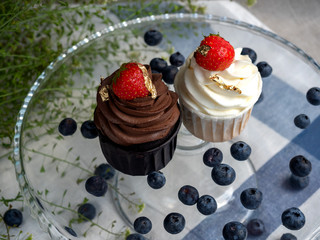 two cream cakes with strawberries and potal on a stand. 
top view